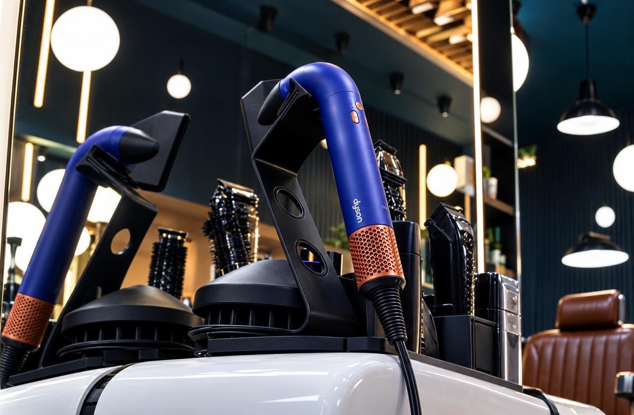 Sèche-cheveux Dyson bleus sur leurs supports, avec brosses et tondeuses devant un miroir