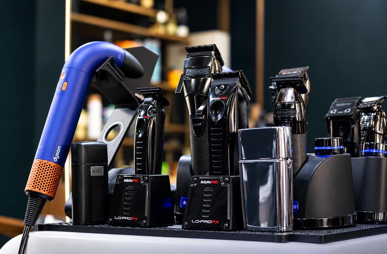 Tondeuses BaBylissPRO et Wahl sur leurs bases de charge, avec un sèche-cheveux Dyson